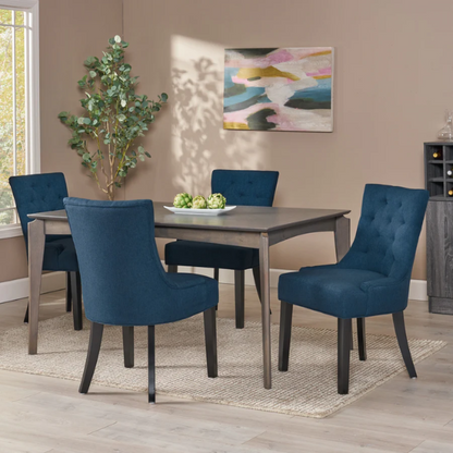 Set of four navy blue upholstered dining chairs featuring diamond tufted backs, armless design, sloped sides, and espresso brown wooden legs.

