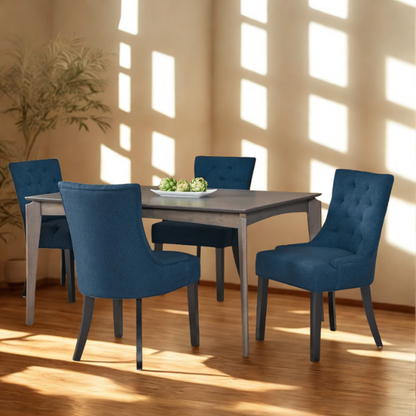 Set of four navy blue upholstered dining chairs featuring diamond tufted backs, armless design, sloped sides, and espresso brown wooden legs.

