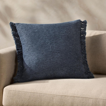 Navy cotton blend throw pillow with fringe, 22x22 square decorative cushion styled on a neutral sofa for bold, modern interior decor.


