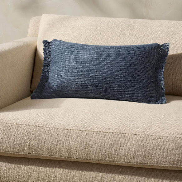 Navy lumbar throw pillow with fringe, rectangular 13x21 design, cotton blend fabric, styled on a modern sofa for cozy interior decor.

