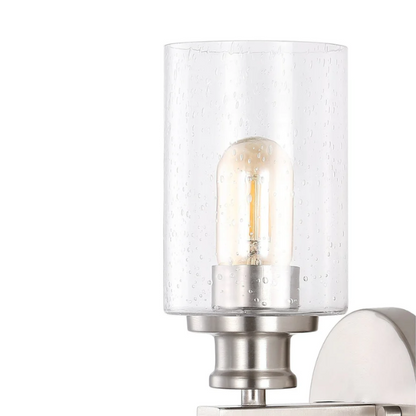 Brushed nickel wall sconce with two clear seeded glass cylinder shades and Edison-style LED bulbs, perfect for bathrooms or hallway accent lighting

