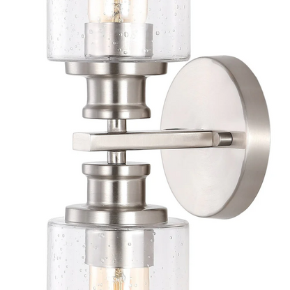 Brushed nickel wall sconce with two clear seeded glass cylinder shades and Edison-style LED bulbs, perfect for bathrooms or hallway accent lighting


