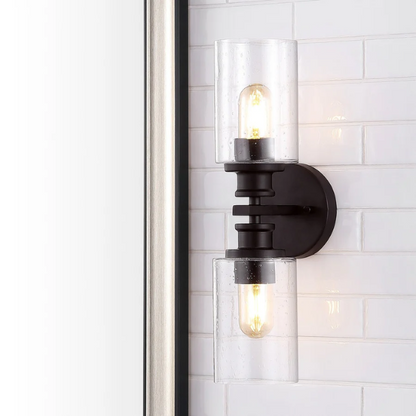 Oil-rubbed bronze wall sconce with dual clear seeded glass cylinder shades and Edison-style LED bulbs, perfect for rustic, farmhouse, or traditional interiors

