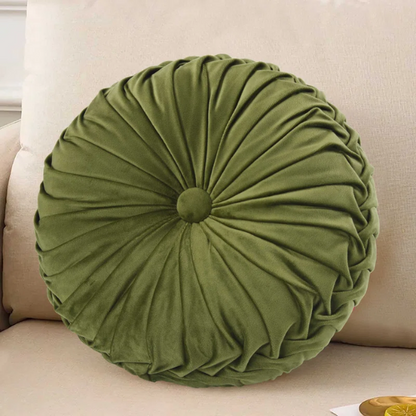 Olive green velvet round throw pillows with hand-pleated detailing and button center, styled on a beige sofa for a warm, inviting look.

