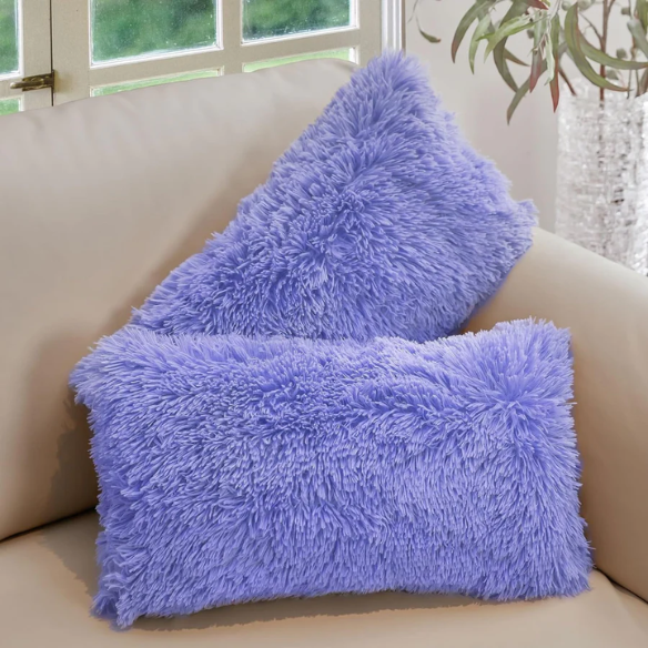 Set of two periwinkle faux fur throw pillows with fluffy texture on a light grey modern couch

