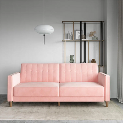 Pink velvet convertible sofa with tufted split-back design, square arms, and tapered brown wood legs, easily converting into a twin-size sleeper.