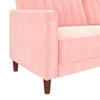 Pink velvet convertible sofa with tufted split-back design, square arms, and tapered brown wood legs, easily converting into a twin-size sleeper.
