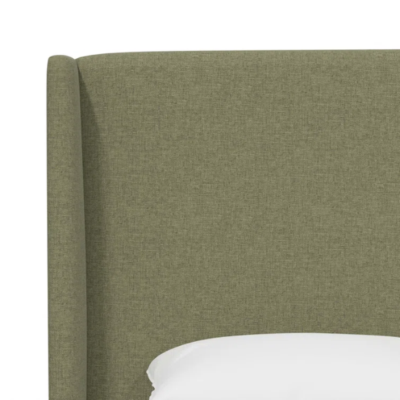 Avocado green king-size upholstered bed in linen fabric with wingback headboard and low-profile black metal legs.

