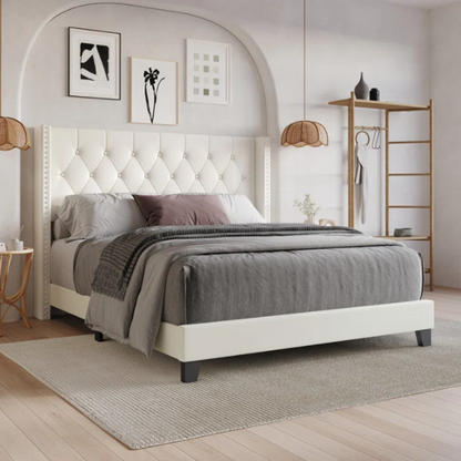 Beige queen-size bed with faux leather upholstery, wingback tufted headboard, nailhead trim, and low-profile wooden frame.

