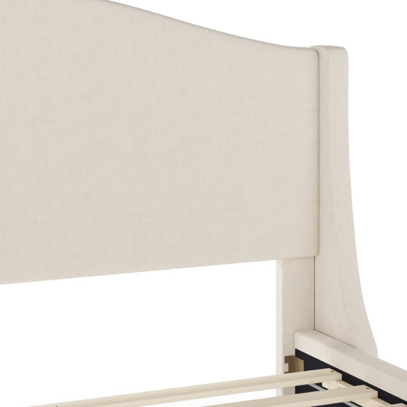Full-size beige upholstered platform bed with curved wingback headboard, cushioned side rails, and tapered wooden legs, shown in a modern bedroom setting.

