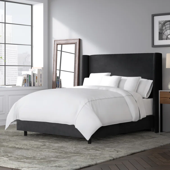 Black king-size upholstered bed with velvet fabric, wingback headboard, and low-profile black metal legs.

