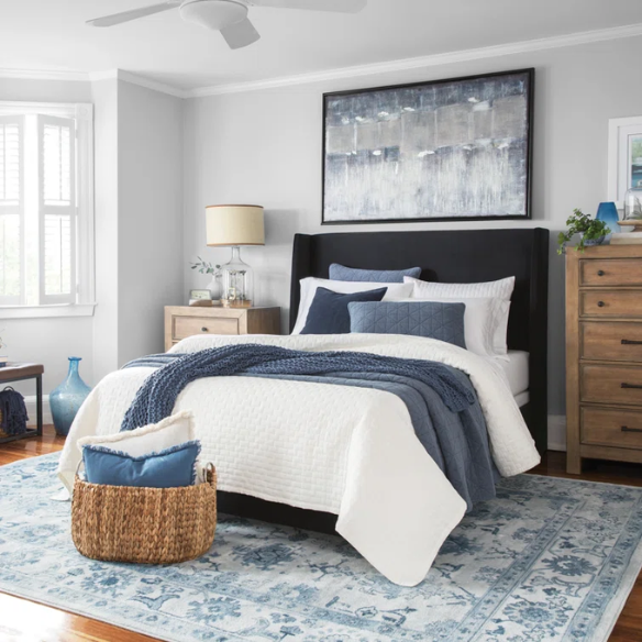 Black king-size upholstered bed with velvet fabric, wingback headboard, and low-profile black metal legs.

