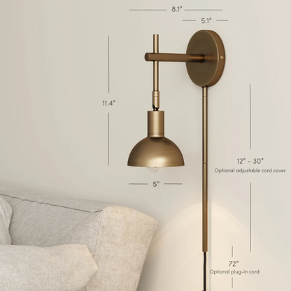 Brass plug-in wall sconce with adjustable swing arm and bell shade, featuring a built-in switch and cord cover for modern bedroom or reading nook lighting

