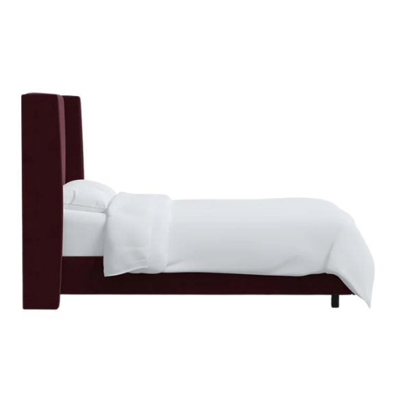 Burgundy king-size upholstered bed in velvet fabric with wingback headboard and low-profile black metal legs.

