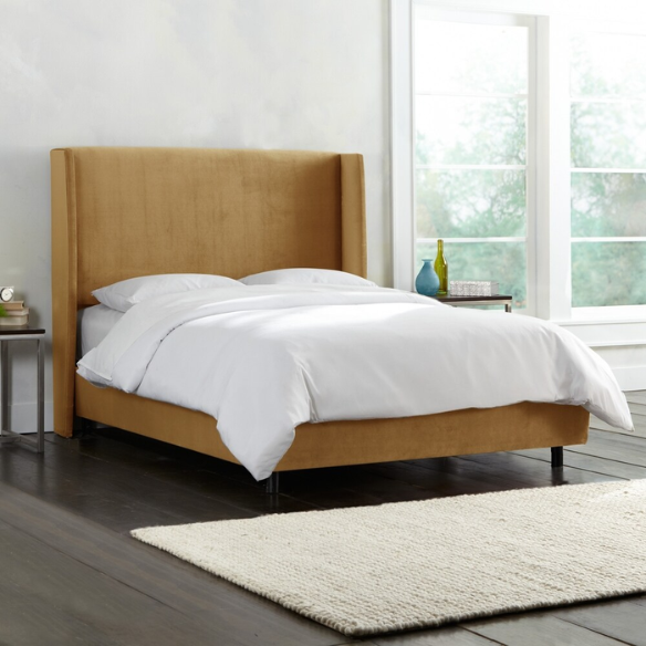 Camel king-size upholstered bed in velvet fabric with wingback headboard and low-profile black metal legs.


