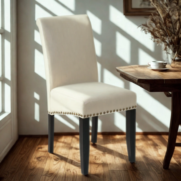 Cream faux leather Parsons chair with scrolled high back, antique bronze nailhead trim, and solid wood legs