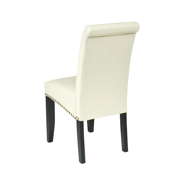 Cream faux leather Parsons chair with scrolled high back, antique bronze nailhead trim, and solid wood legs