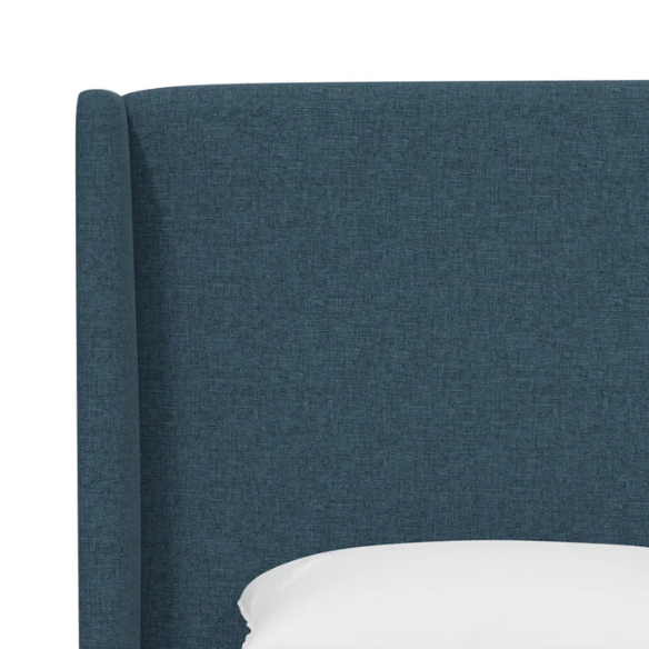 Dark blue king-size upholstered bed in linen fabric with wingback headboard and black metal legs.

