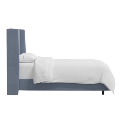 Dusty blue king-size upholstered bed in linen fabric with wingback headboard and low-profile black metal legs.

