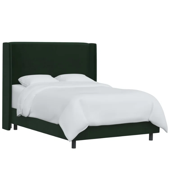 Emerald green king-size upholstered bed in velvet fabric with wingback headboard and low-profile black metal legs.

