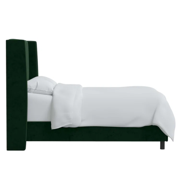 Emerald green king-size upholstered bed in velvet fabric with wingback headboard and low-profile black metal legs.

