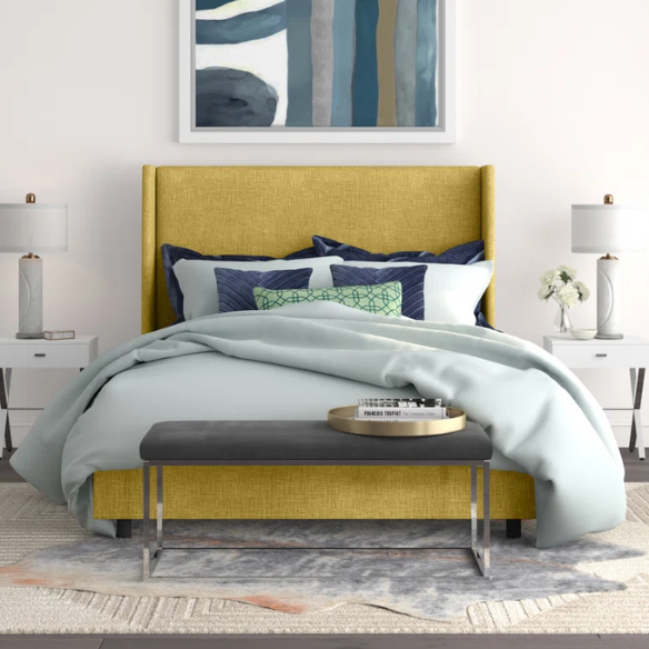 Golden yellow king-size upholstered bed in linen fabric with wingback headboard and black metal legs.


