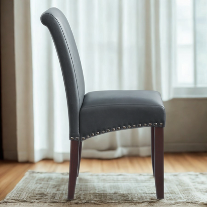 Grey leather Parsons chair with high back, scrolled shoulders, antique bronze nailhead trim, and solid wood legs
