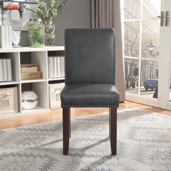 Grey leather Parsons chair with high back, scrolled shoulders, antique bronze nailhead trim, and solid wood legs