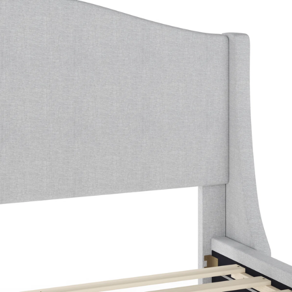 Full-size grey upholstered platform bed with curved wingback headboard, cushioned side rails, and tapered wooden legs in a stylish modern bedroom.

