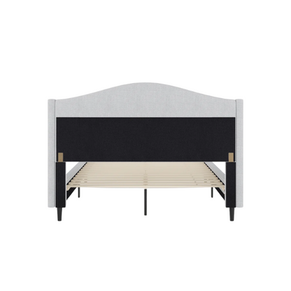 Full-size grey upholstered platform bed with curved wingback headboard, cushioned side rails, and tapered wooden legs in a stylish modern bedroom.

