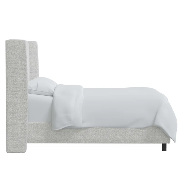 Ivory king-size upholstered bed in bouclé fabric with wingback headboard and low-profile black metal legs.

