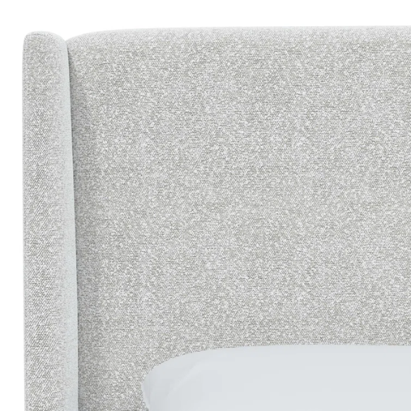 Ivory king-size upholstered bed in bouclé fabric with wingback headboard and low-profile black metal legs.

