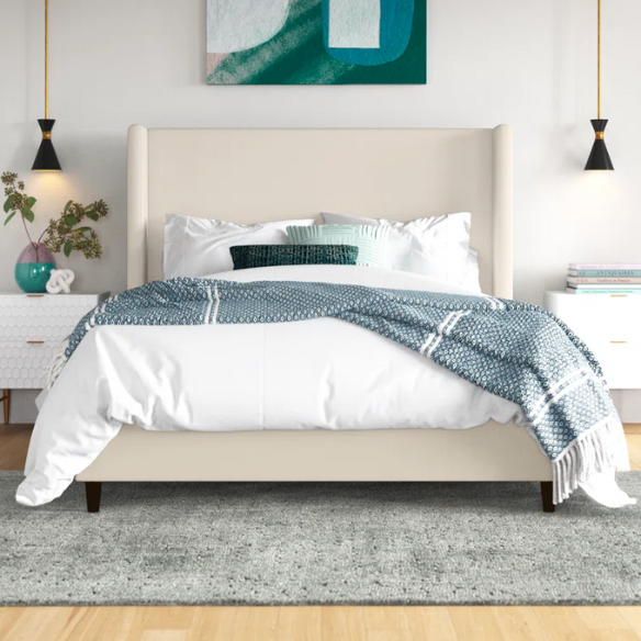 Light cream canvas upholstered queen-size bed with extra-tall wingback tufted headboard and black tapered legs.

