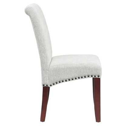 Light grey upholstered Parsons chair with scrolled high back, antique bronze nailhead trim, and solid wood legs