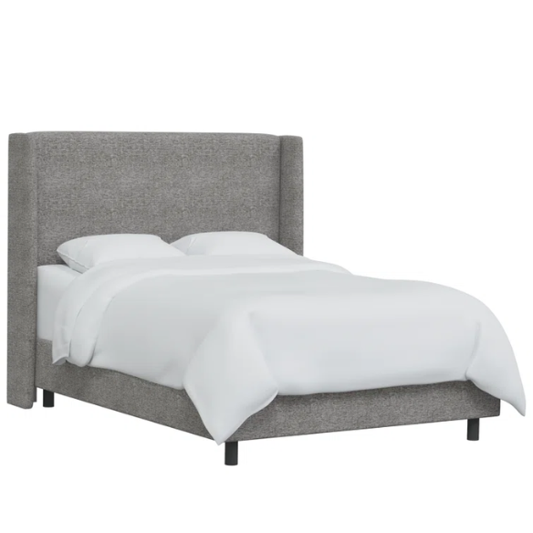 Light grey king-size upholstered bed in tweed fabric with wingback headboard and low-profile black metal legs.

