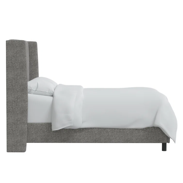 Light grey king-size upholstered bed in tweed fabric with wingback headboard and low-profile black metal legs.

