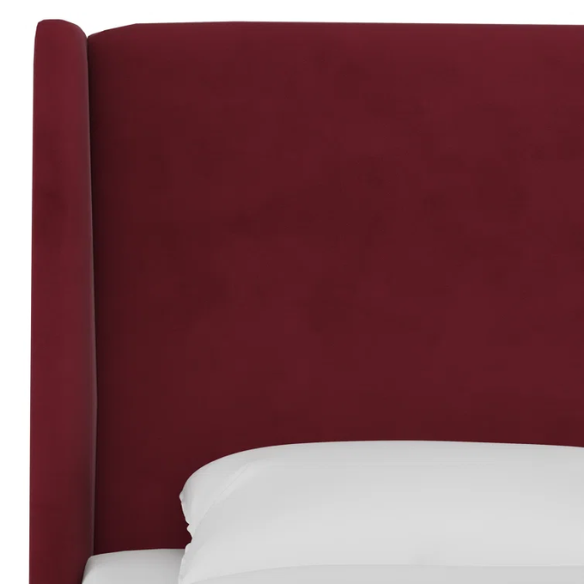 Maroon king-size upholstered bed in velvet with wingback headboard and low-profile black metal legs.

