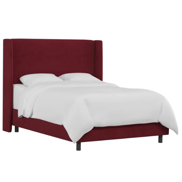 Maroon king-size upholstered bed in velvet with wingback headboard and low-profile black metal legs.

