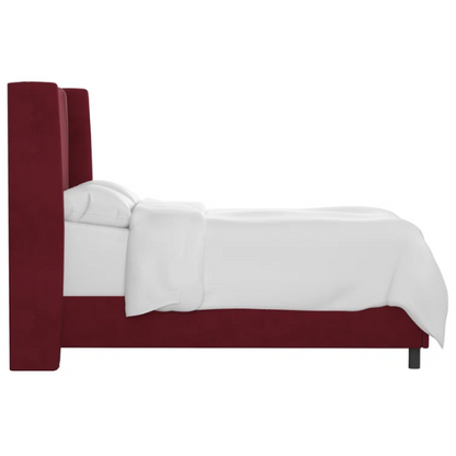 Maroon king-size upholstered bed in velvet with wingback headboard and low-profile black metal legs.

