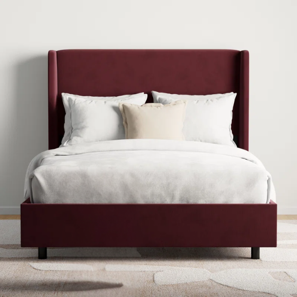 Maroon king-size upholstered bed in velvet with wingback headboard and low-profile black metal legs.

