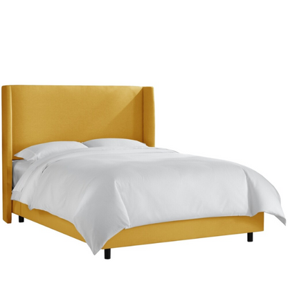 Mustard yellow king-size upholstered bed in linen fabric with wingback headboard and low-profile black metal legs.

