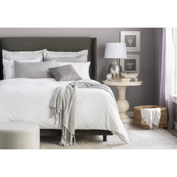 Pewter king-size upholstered bed in velvet fabric with wingback headboard and low-profile black metal legs.

