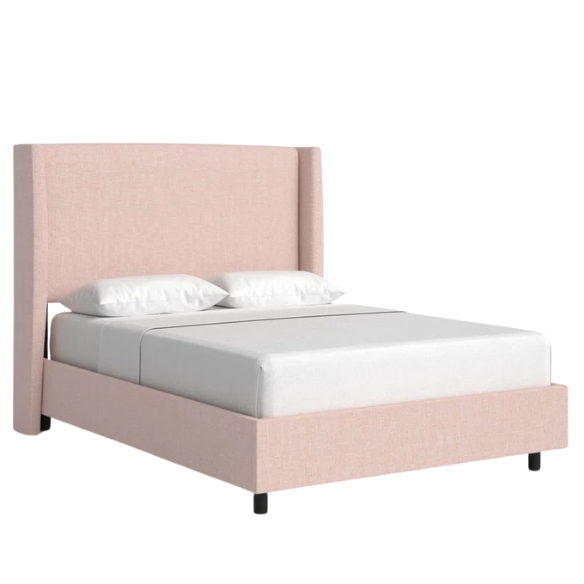 Rosy pink king-size upholstered bed in linen with wingback headboard and black metal legs.

