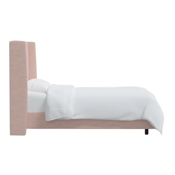 Rosy pink king-size upholstered bed in linen with wingback headboard and black metal legs.

