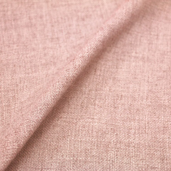Rosy pink king-size upholstered bed in linen with wingback headboard and black metal legs.


