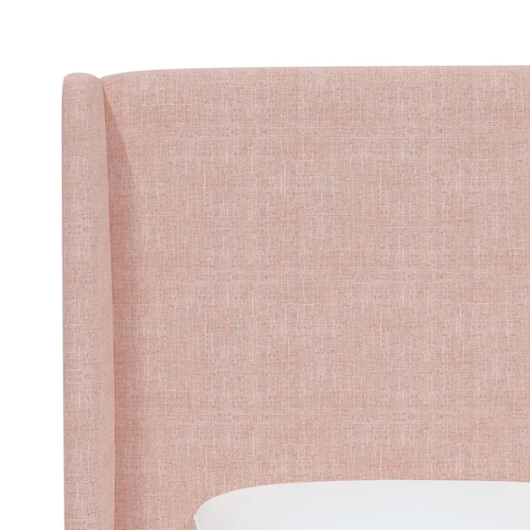 Rosy pink king-size upholstered bed in linen with wingback headboard and black metal legs.

