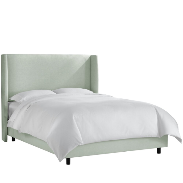 Sage green king-size upholstered bed in linen fabric with wingback headboard and low-profile black metal legs.

