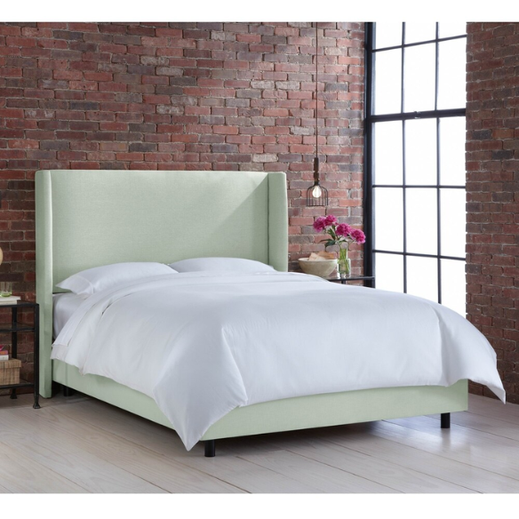 Sage green king-size upholstered bed in linen fabric with wingback headboard and low-profile black metal legs.

