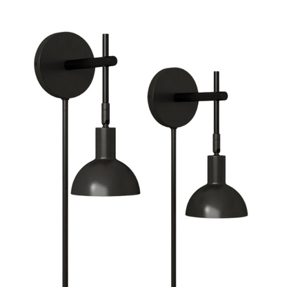Set of 2 matte black plug-in wall sconces with adjustable swing arms and bell-shaped shades, ideal for bedside reading or task lighting in modern interiors.