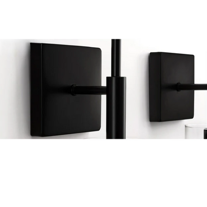 Set of 2 black wall sconces with hand-blown glass cylinder shades and bronze hardware, mountable up or down for modern or farmhouse interiors

